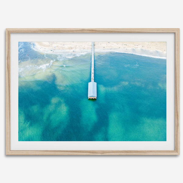 Drone photo of a pier extending into clear blue ocean at Hanalei Beach, Kauai, Hawaii.