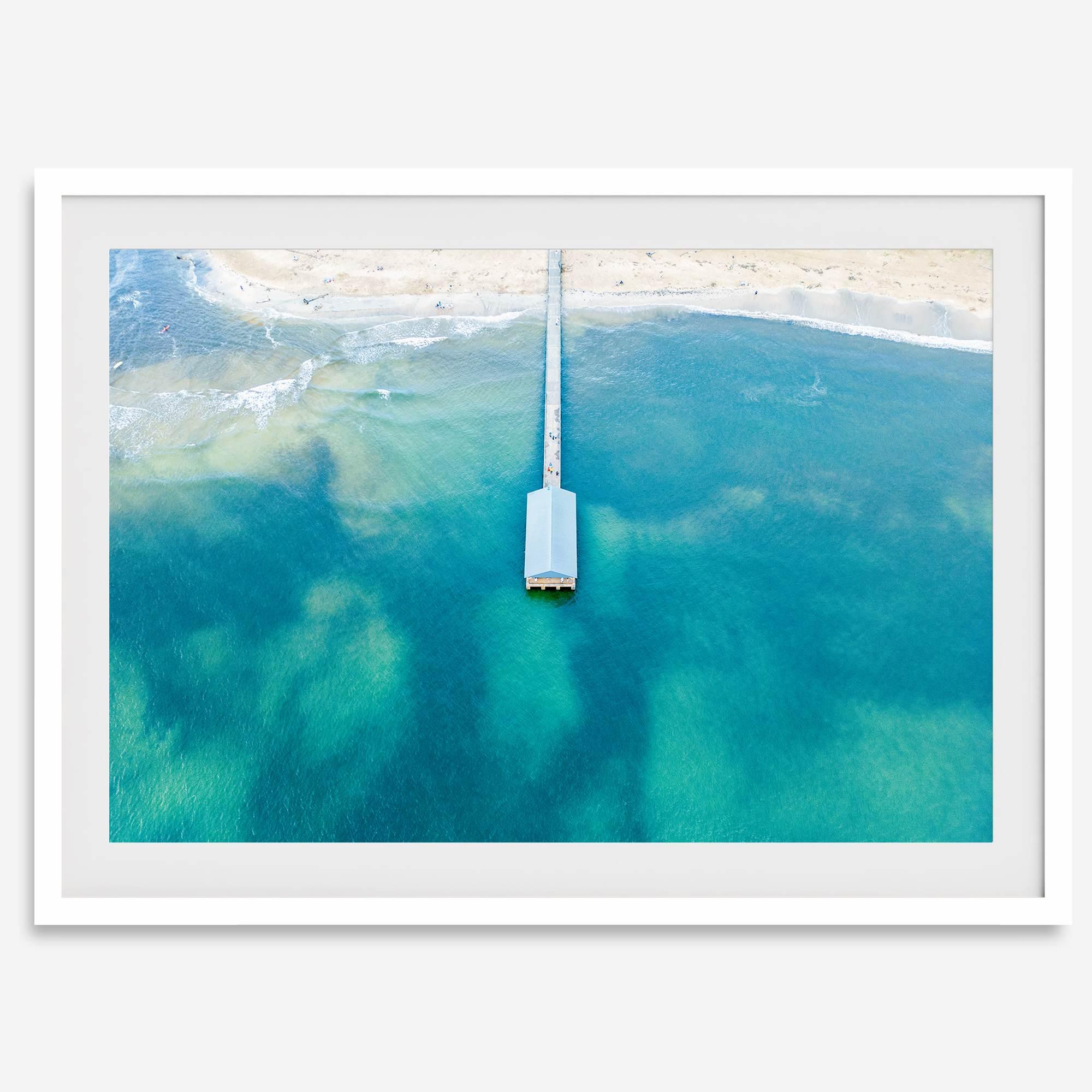 Drone photo of a pier extending into clear blue ocean at Hanalei Beach, Kauai, Hawaii.