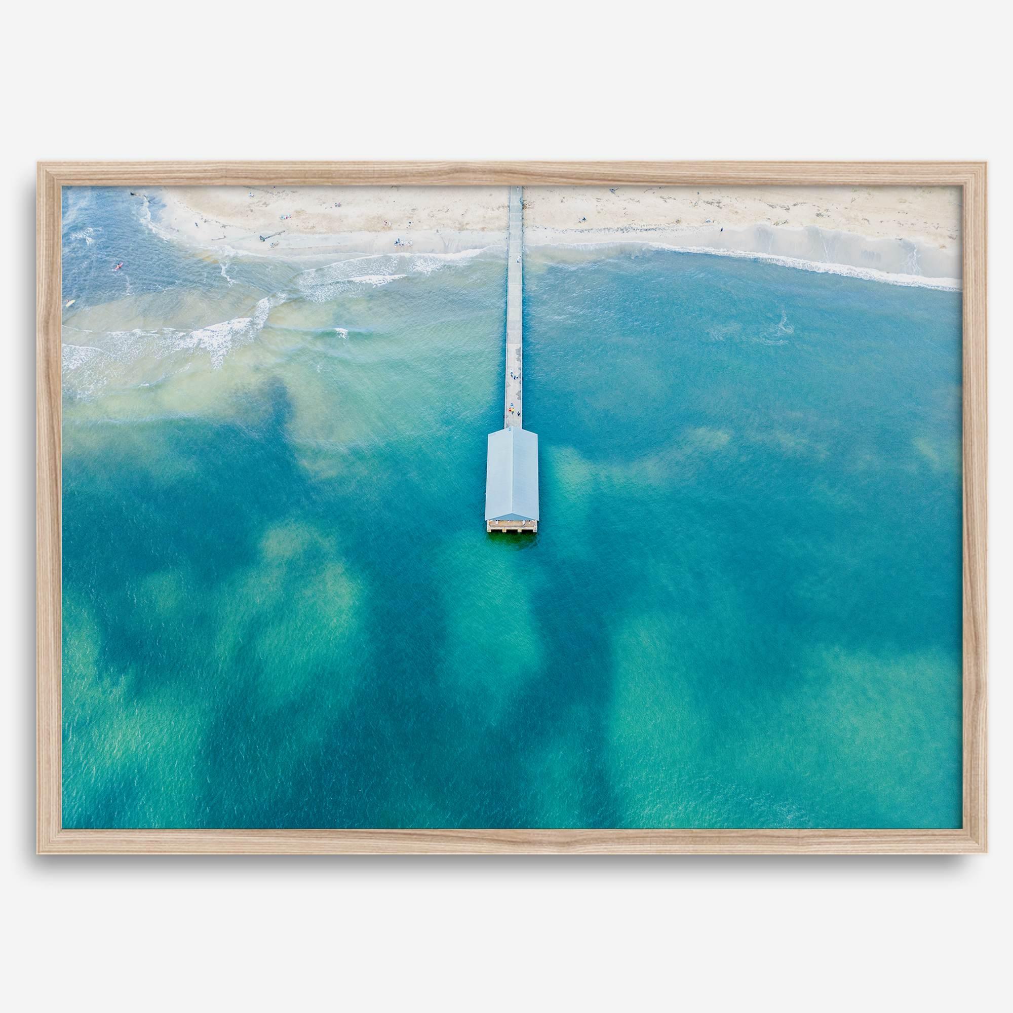 Drone photo of a pier extending into clear blue ocean at Hanalei Beach, Kauai, Hawaii.