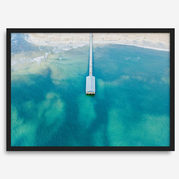 Drone photo of a pier extending into clear blue ocean at Hanalei Beach, Kauai, Hawaii.