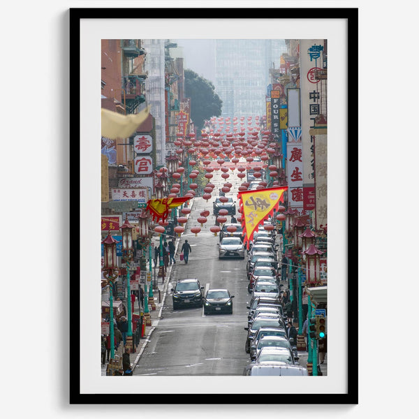 Red lanterns line Grant Avenue in San Francisco’s Chinatown, framed by colorful signs and bustling city life. Available as a framed or unframed print.