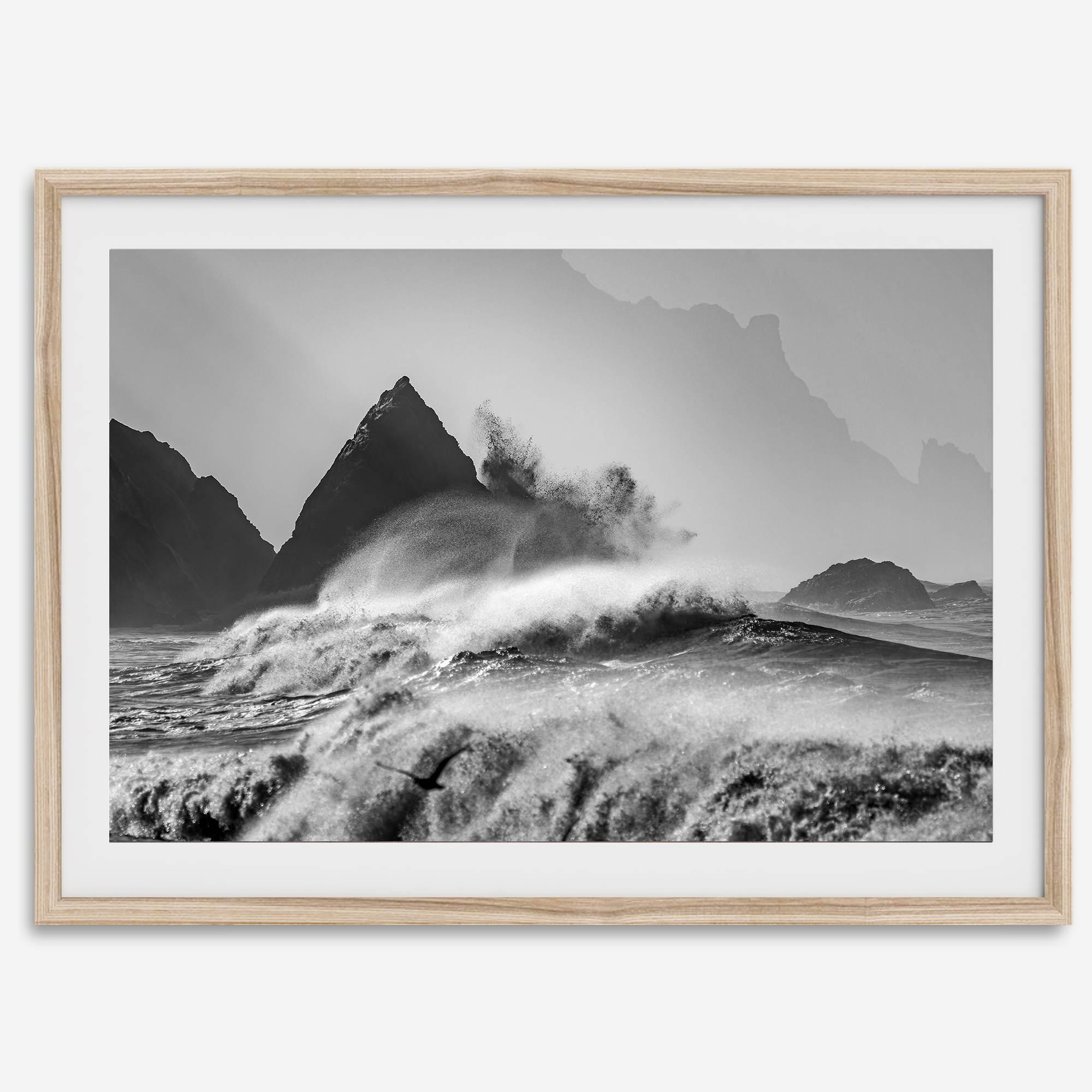 Black and white crashing waves wall art with dramatic ocean spray, jagged cliffs, and a moody atmosphere.