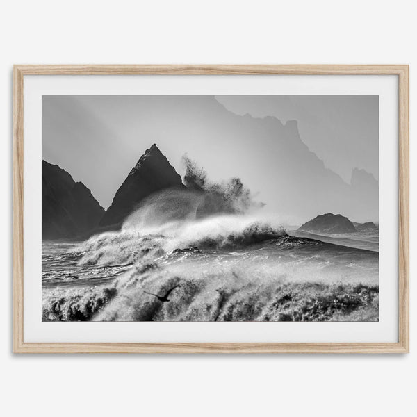 Black and white crashing waves wall art with dramatic ocean spray, jagged cliffs, and a moody atmosphere.
