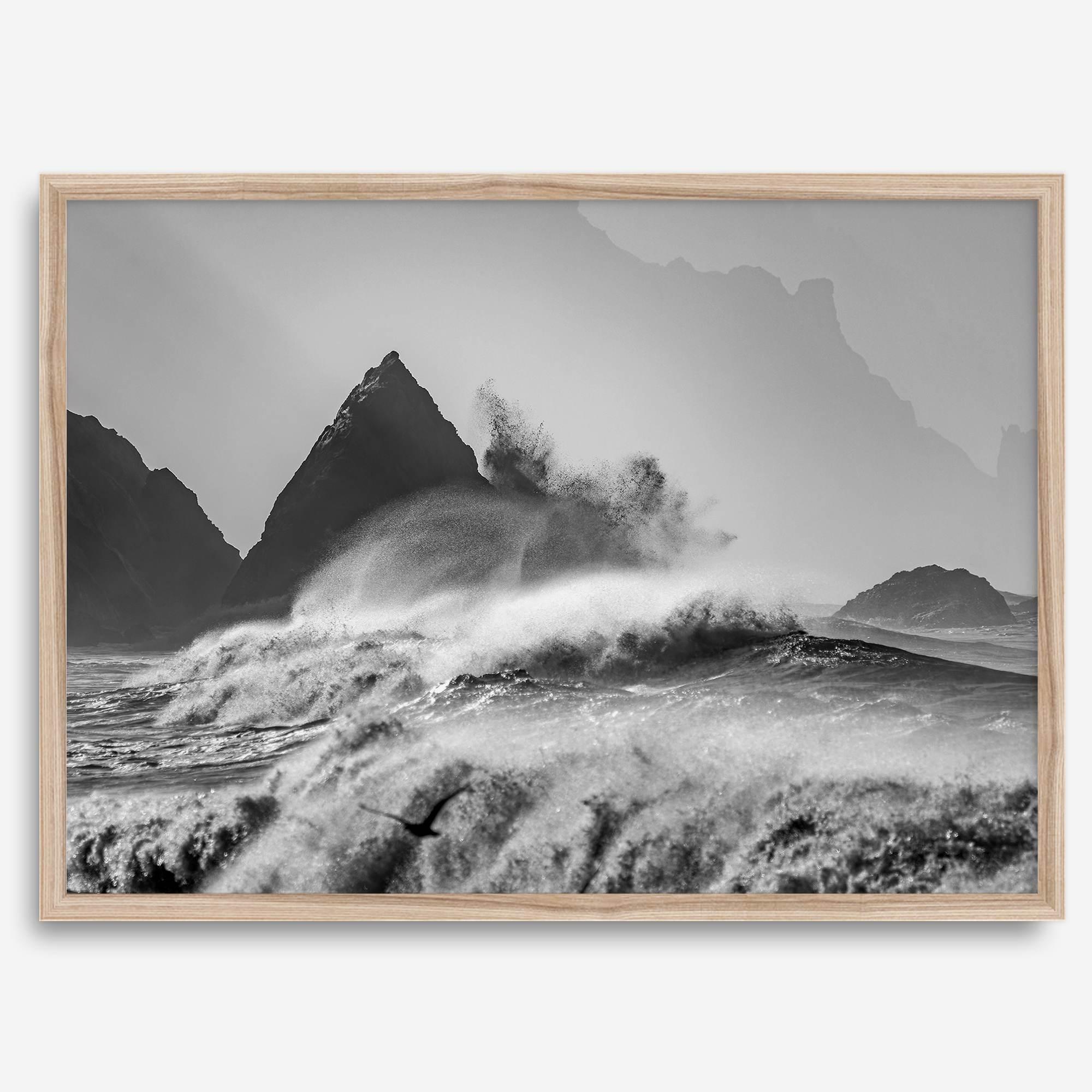 Black and white crashing waves wall art with dramatic ocean spray, jagged cliffs, and a moody atmosphere.