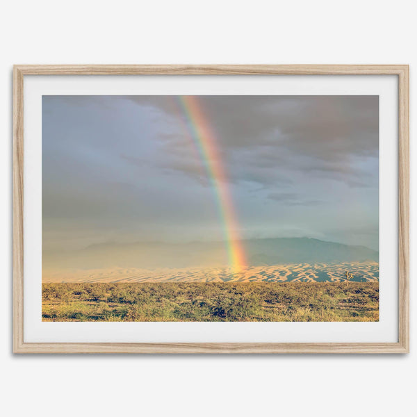 Desert landscape artwork of a rainbow over Arizona sand dunes with distant mountains.
