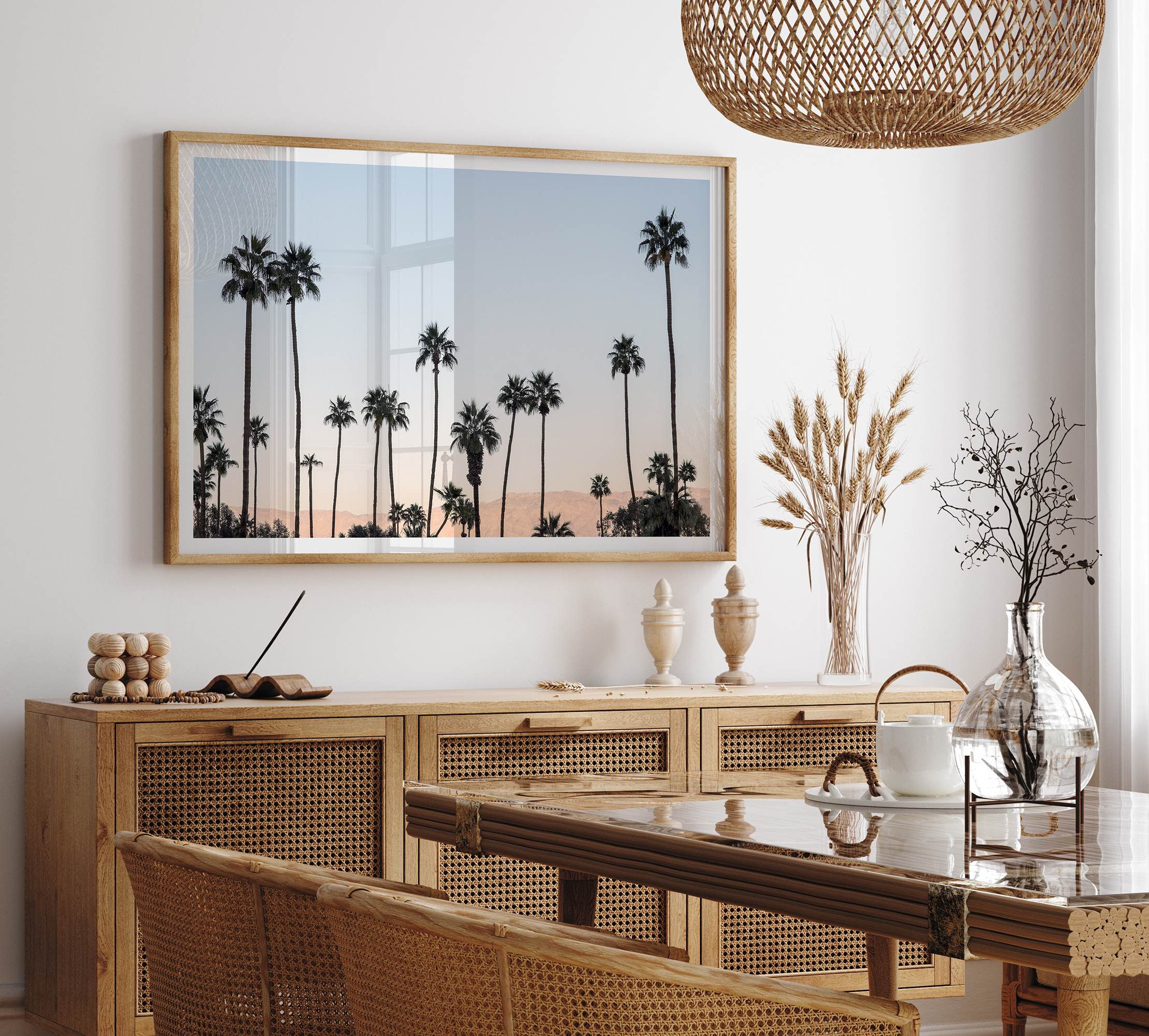 Silhouetted palm trees in Palm Springs under a clear blue sky with pink desert mountains in background