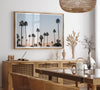 Silhouetted palm trees in Palm Springs under a clear blue sky with pink desert mountains in background