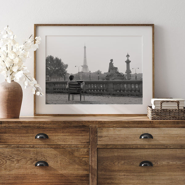 Black-and-white Paris wall art featuring a woman reading in a park with the Eiffel Tower in the background.