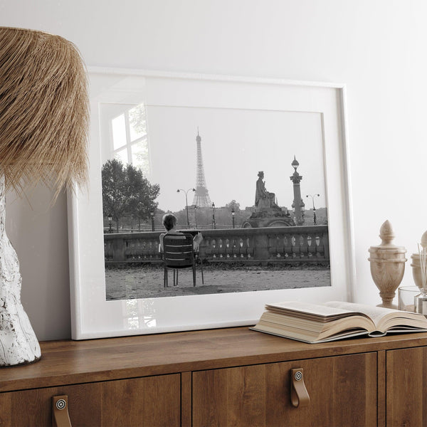 Black-and-white Paris wall art featuring a woman reading in a park with the Eiffel Tower in the background.