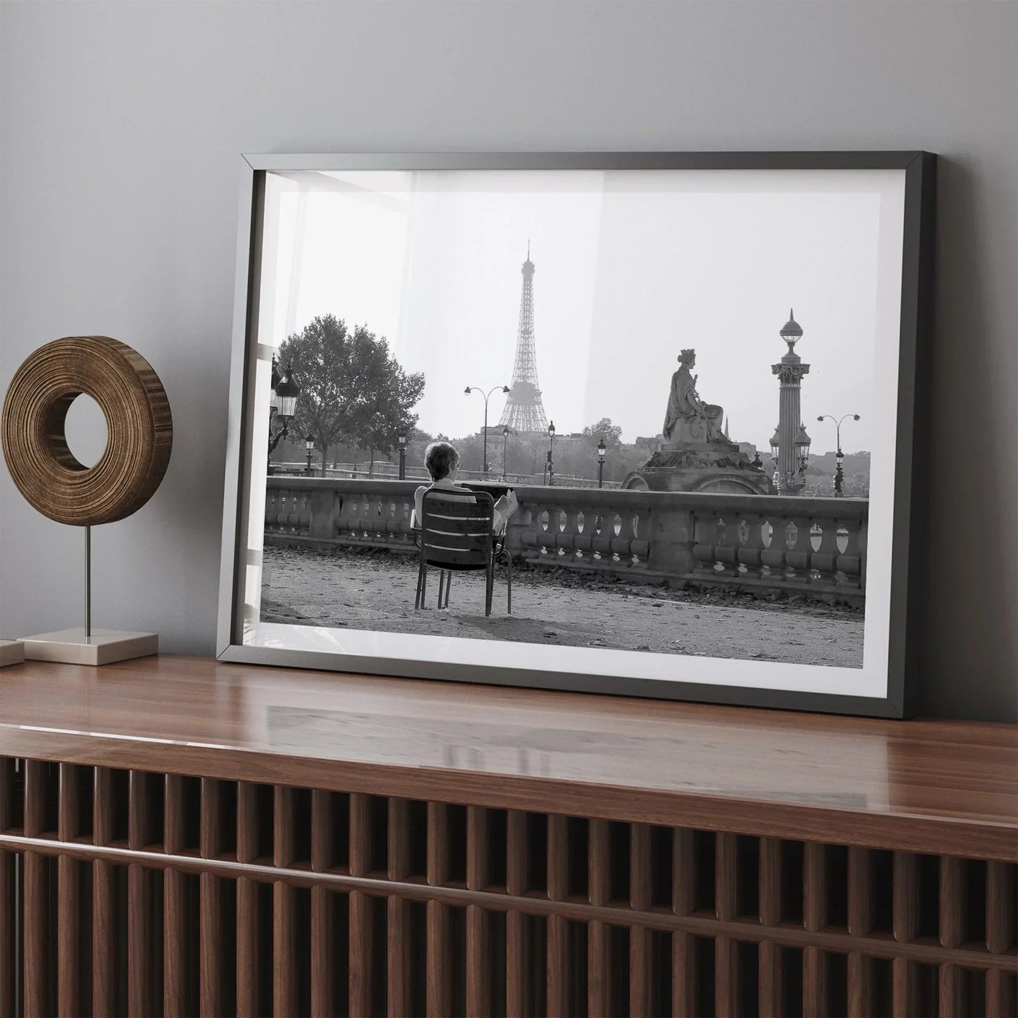Black-and-white Paris wall art featuring a woman reading in a park with the Eiffel Tower in the background.