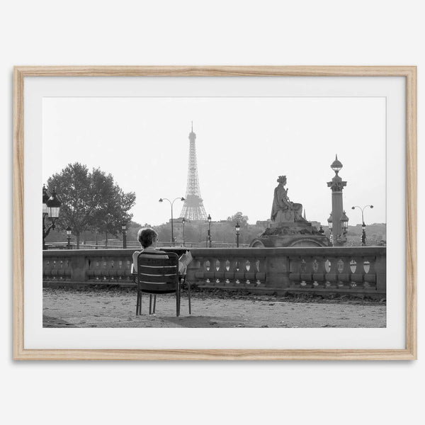 Black-and-white Paris wall art featuring a woman reading in a park with the Eiffel Tower in the background.