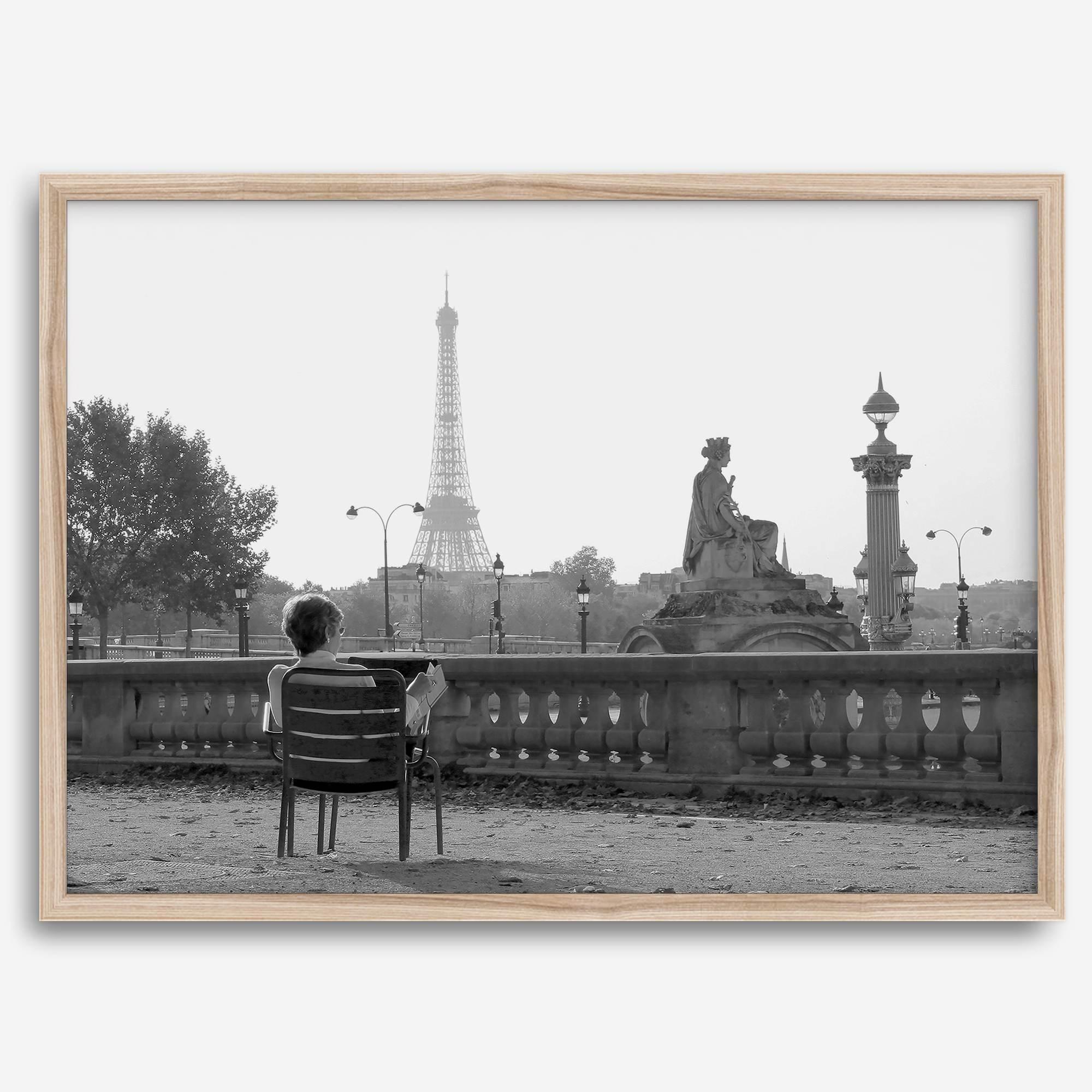 Black-and-white Paris wall art featuring a woman reading in a park with the Eiffel Tower in the background.