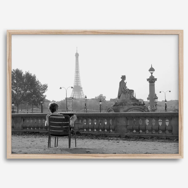 Black-and-white Paris wall art featuring a woman reading in a park with the Eiffel Tower in the background.