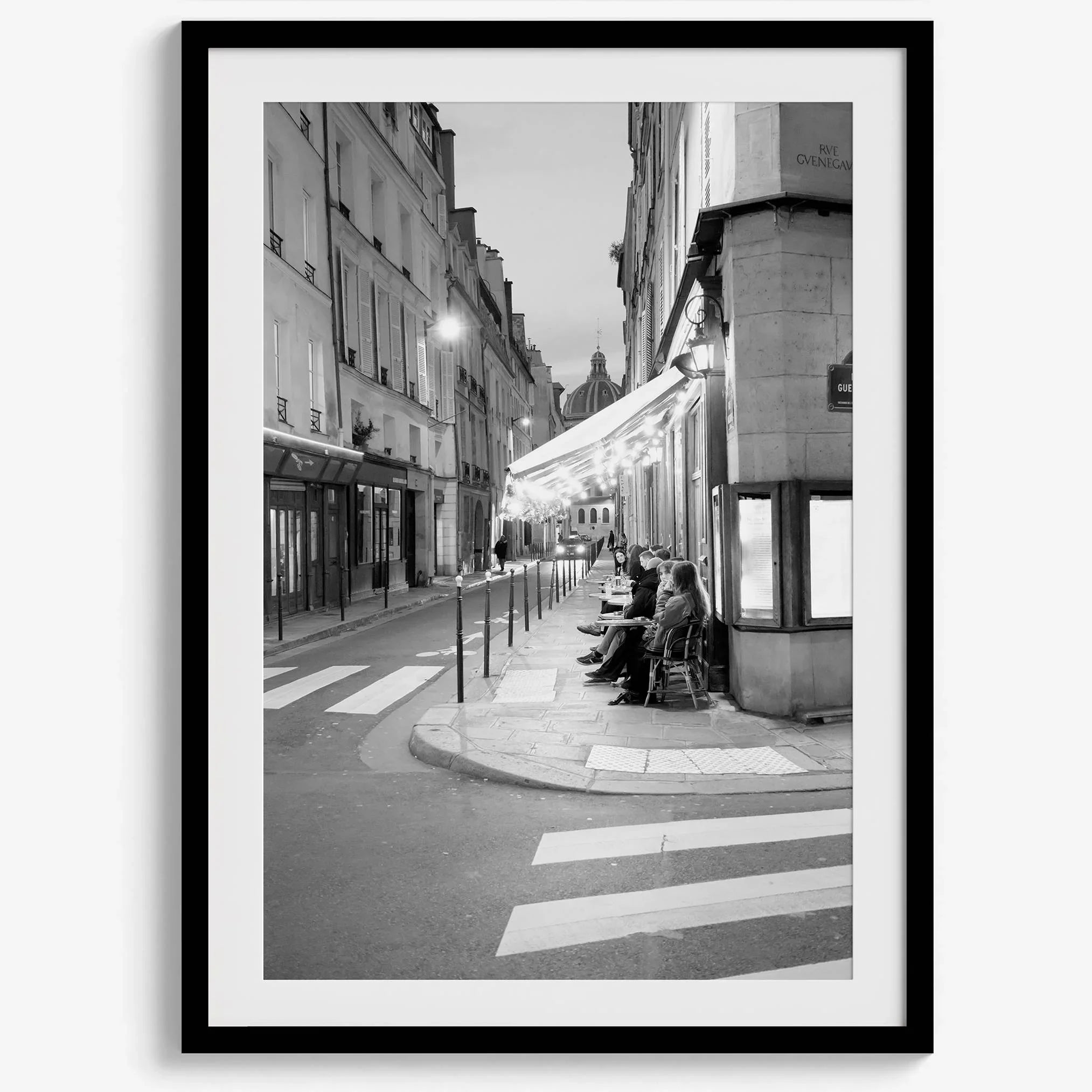 Paris street photography showing glowing café at dusk on Rue de l’Université in black and white.