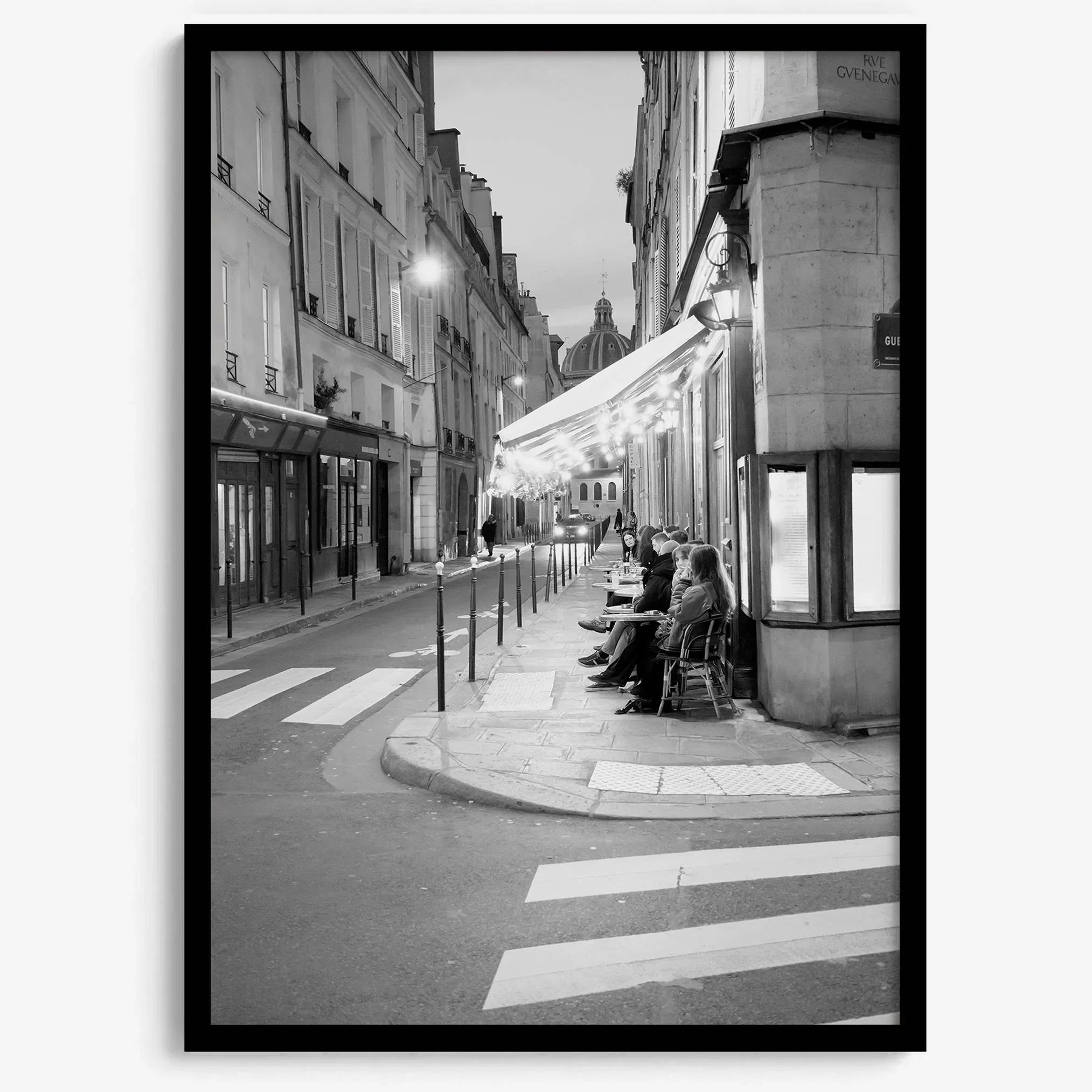 Paris street photography showing glowing café at dusk on Rue de l’Université in black and white.