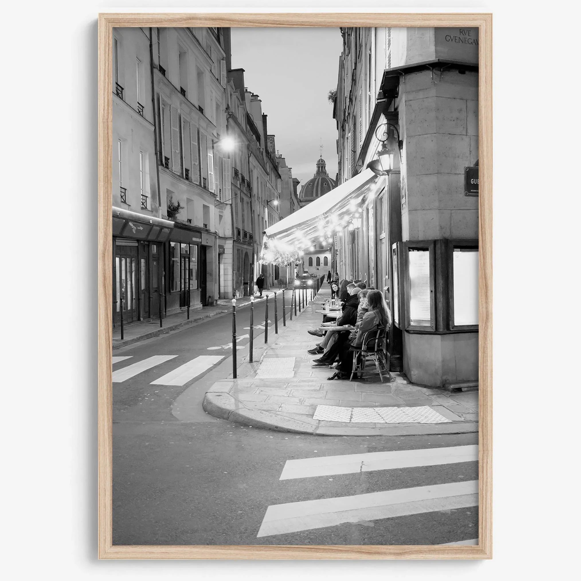Paris street photography showing glowing café at dusk on Rue de l’Université in black and white.
