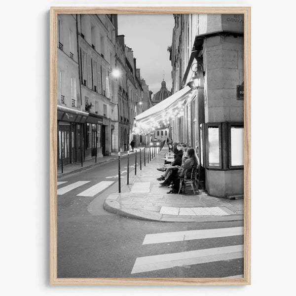 Paris street photography showing glowing café at dusk on Rue de l’Université in black and white.