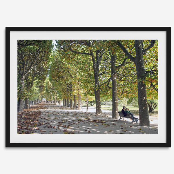 A fine art Paris print of Jardin des Tuileries in fall, featuring a couple sitting on a bench beneath vibrant autumn trees, surrounded by golden foliage.
