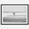 Black and white surfer photography showing a lone surfer on the beach, with waves in the background, capturing minimalist coastal beauty.