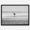 Black and white surfer photography showing a lone surfer on the beach, with waves in the background, capturing minimalist coastal beauty.