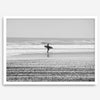 Black and white surfer photography showing a lone surfer on the beach, with waves in the background, capturing minimalist coastal beauty.