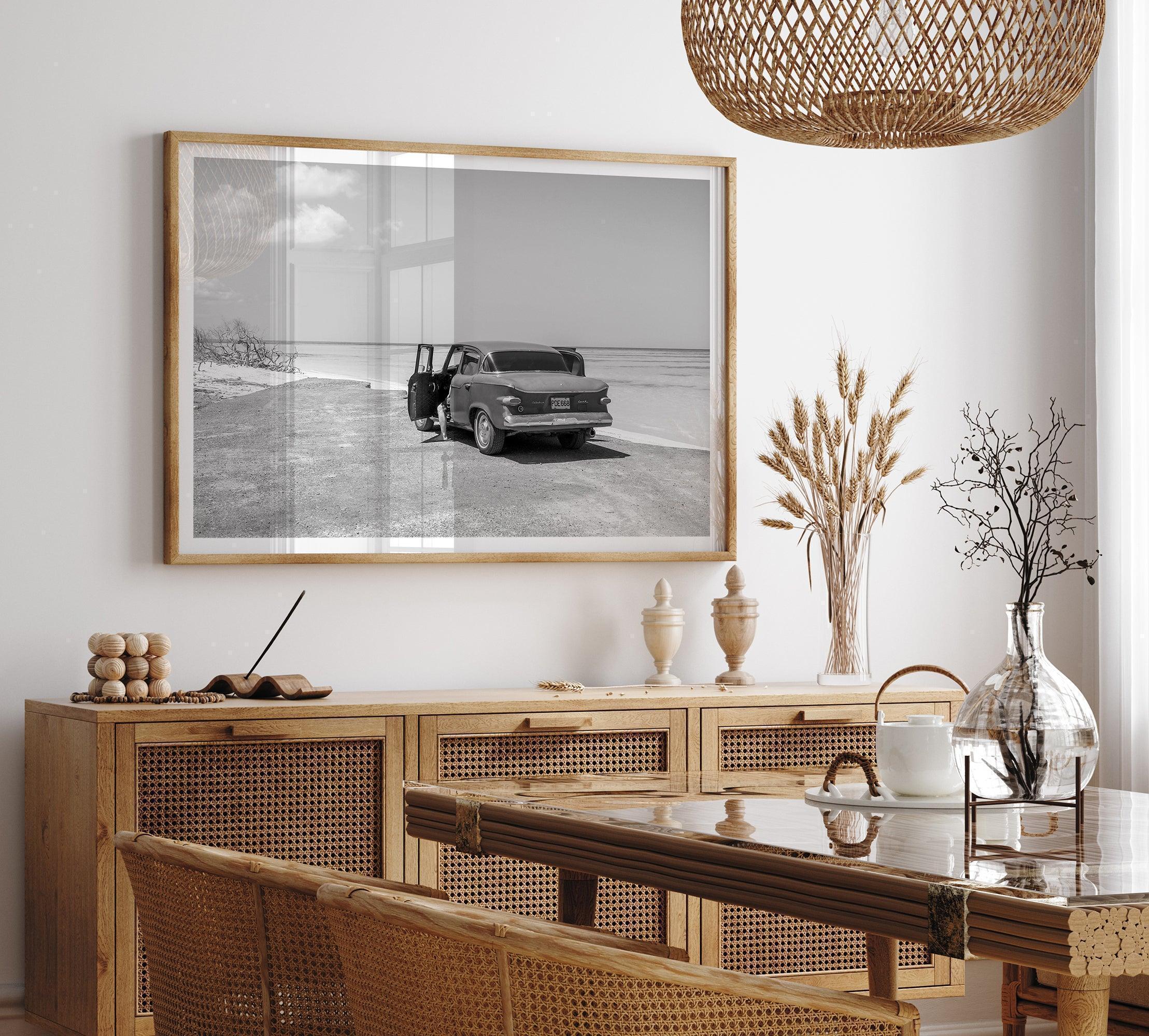 Black and white vintage beach print featuring a classic car parked at the edge of the ocean, capturing a retro coastal scene with timeless charm.