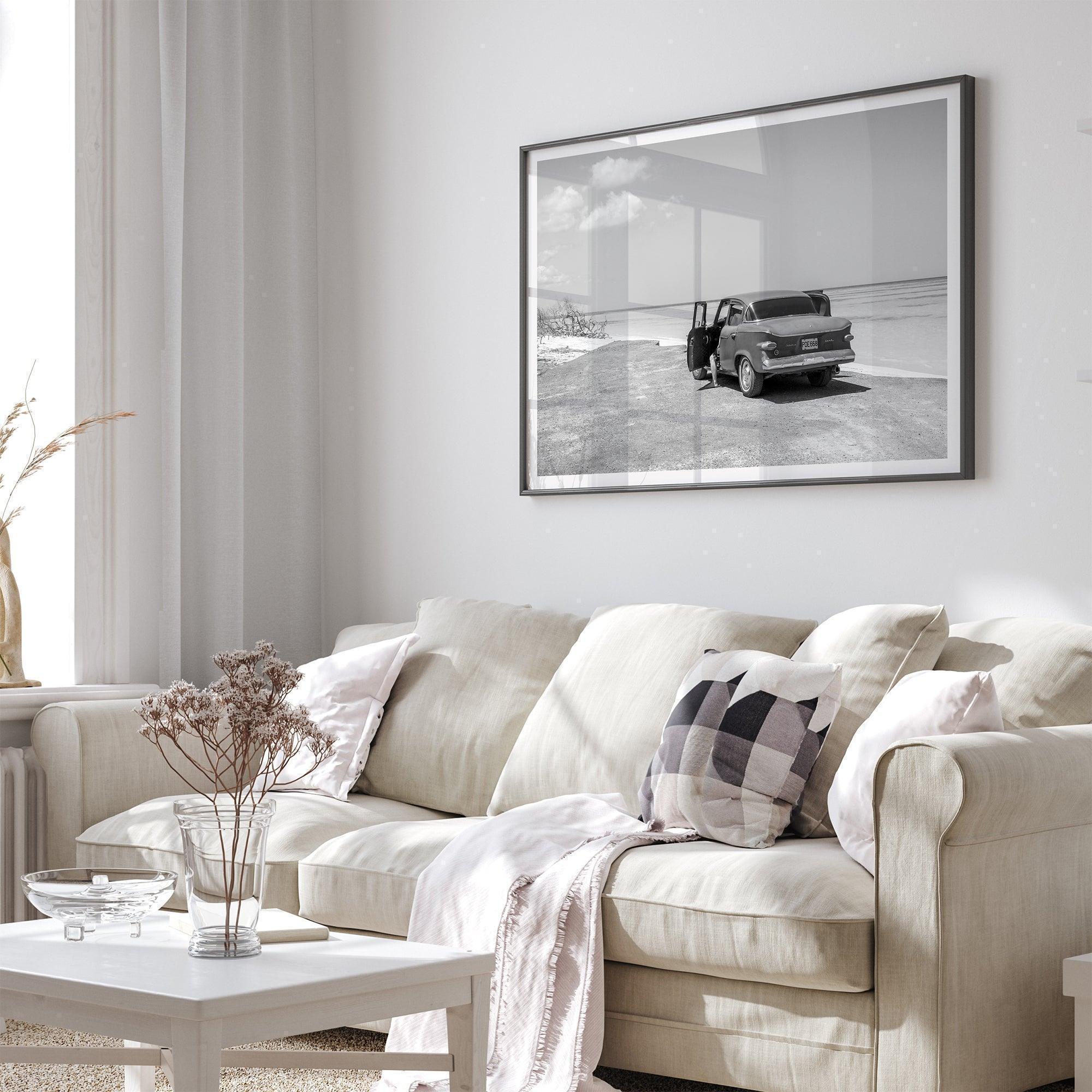 Black and white vintage beach print featuring a classic car parked at the edge of the ocean, capturing a retro coastal scene with timeless charm.