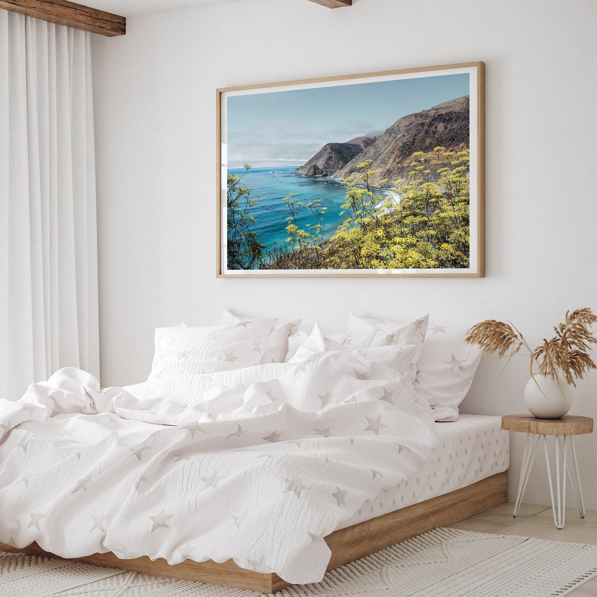 Capture the awe-inspiring coastal beauty with our fine art coastal print. Bixby Bridge spans the cliffs amidst vibrant yellow flowers, complementing the serene blue ocean. Perfect for framed or unframed wall art display.
