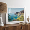 Capture the awe-inspiring coastal beauty with our fine art coastal print. Bixby Bridge spans the cliffs amidst vibrant yellow flowers, complementing the serene blue ocean. Perfect for framed or unframed wall art display.
