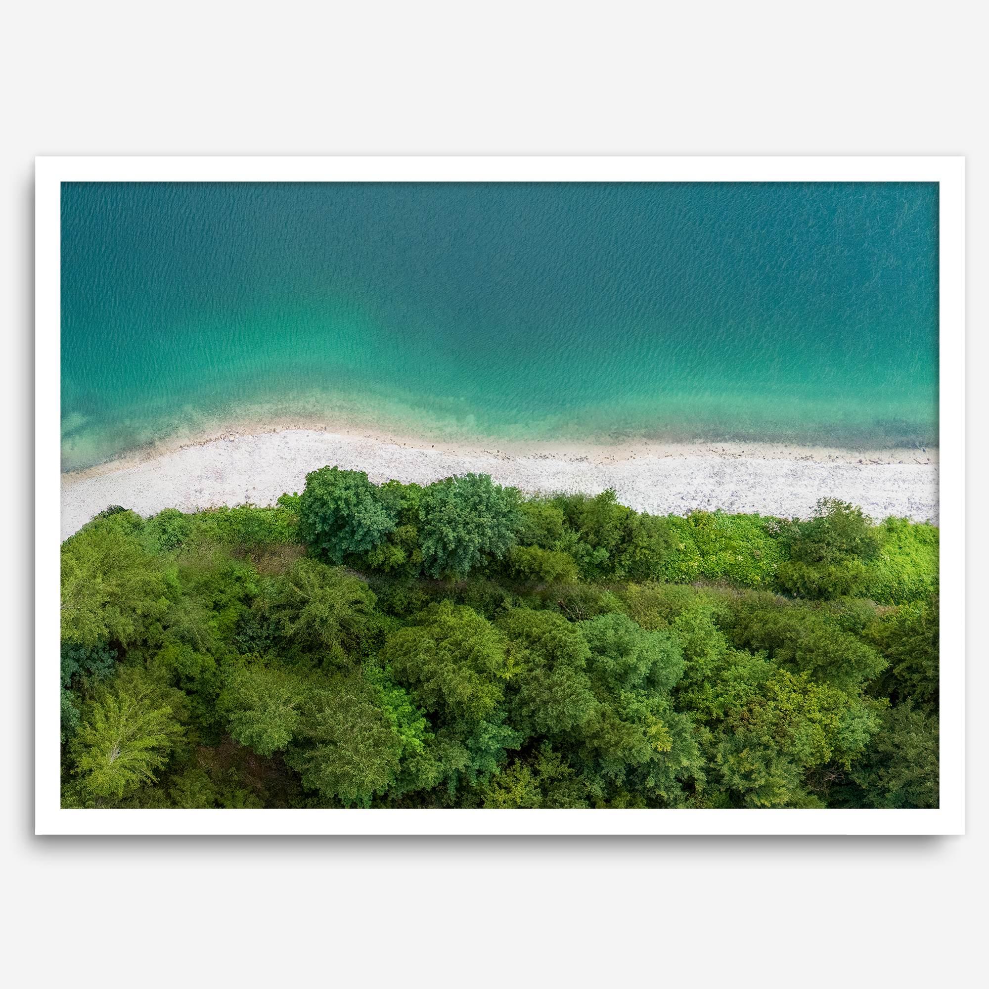 A fine art beach print from above with emerald colors and lush forest.