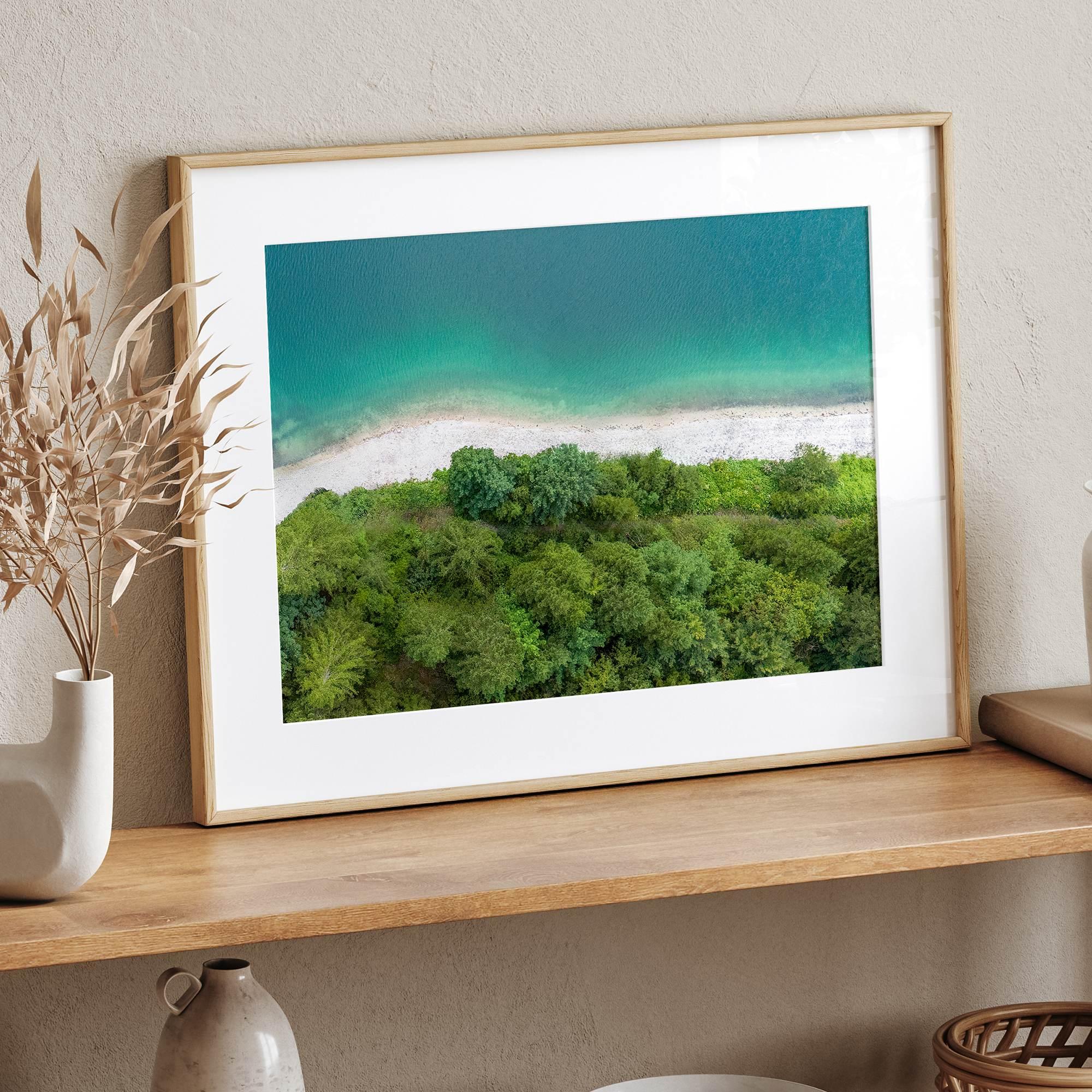A fine art beach print from above with emerald colors and lush forest.