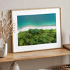 A fine art beach print from above with emerald colors and lush forest.