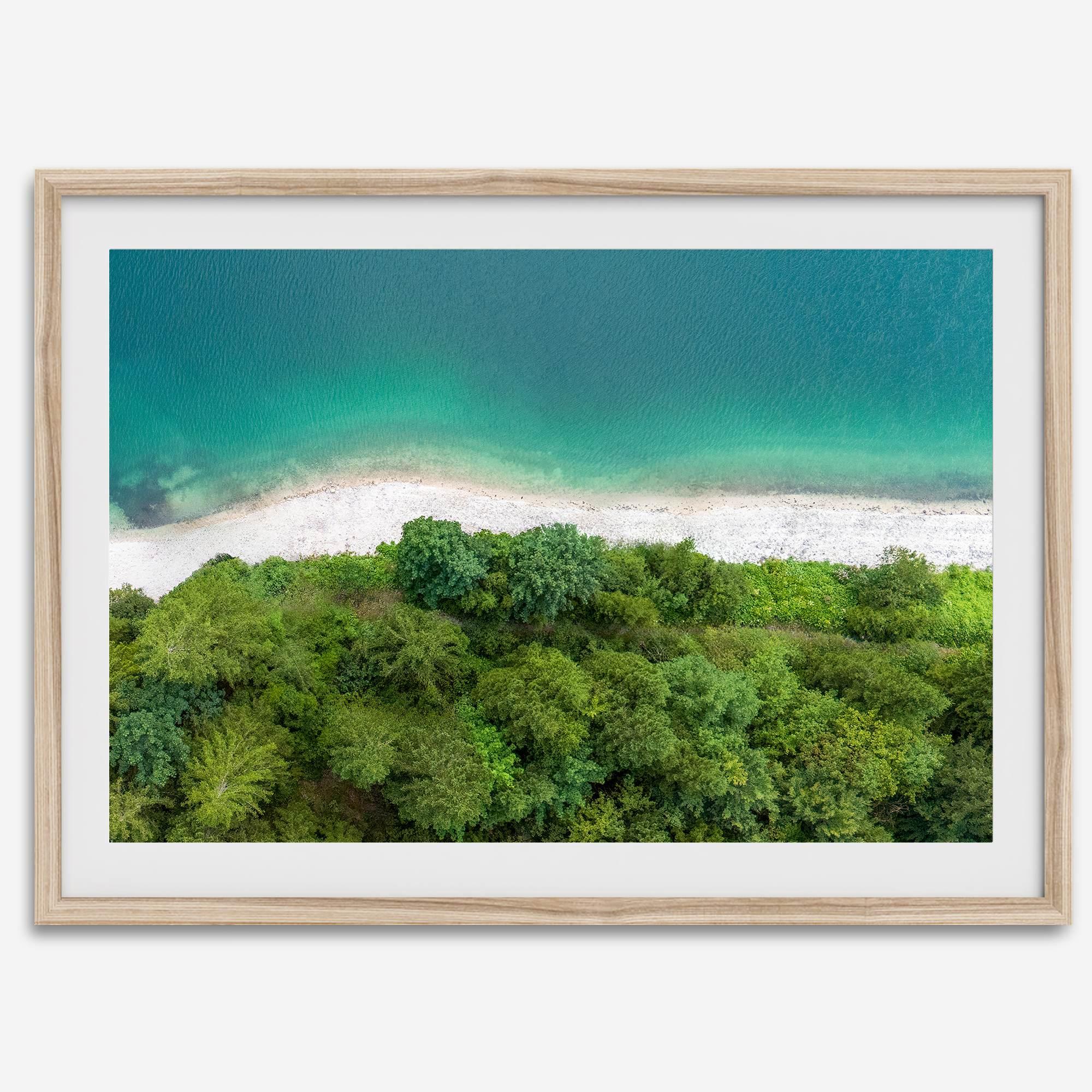 A fine art beach print from above with emerald colors and lush forest.