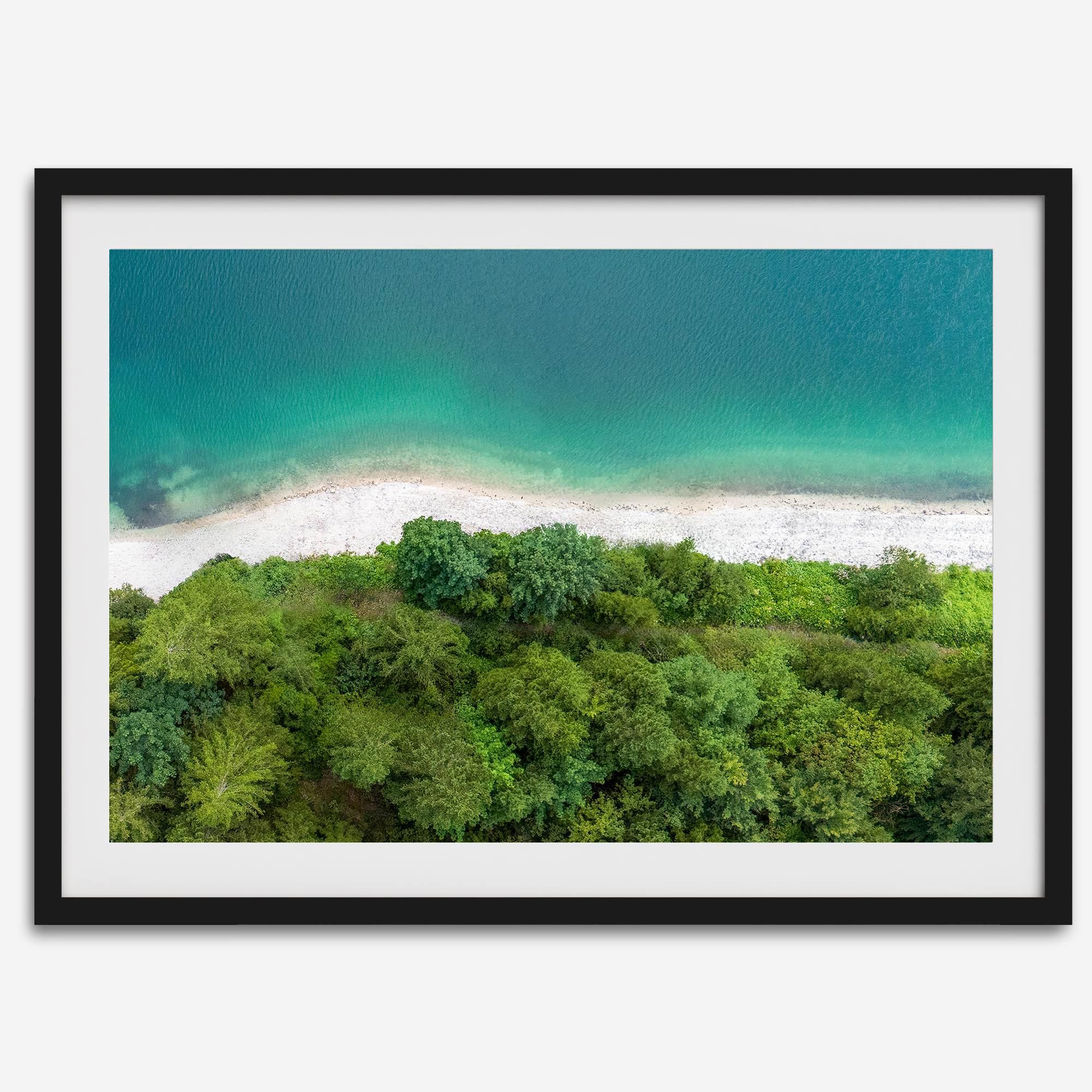 A fine art beach print from above with emerald colors and lush forest.