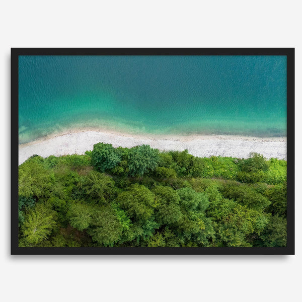 A fine art beach print from above with emerald colors and lush forest.