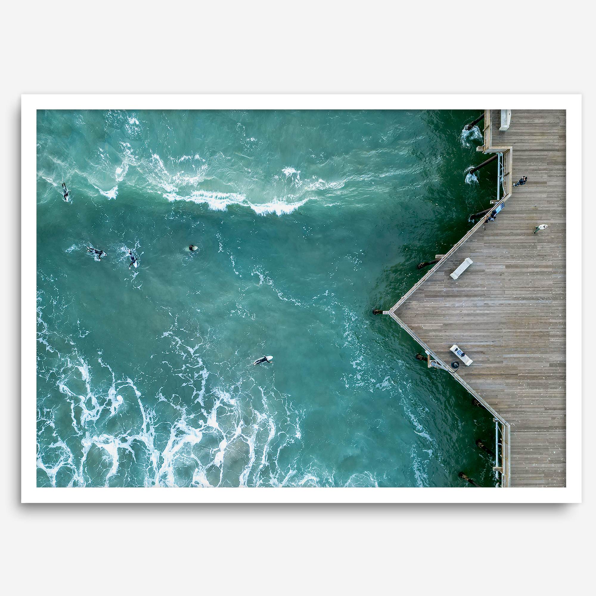 Aerial photo of Pismo Pier with surfers and turquoise ocean waves, ideal for coastal wall decor.