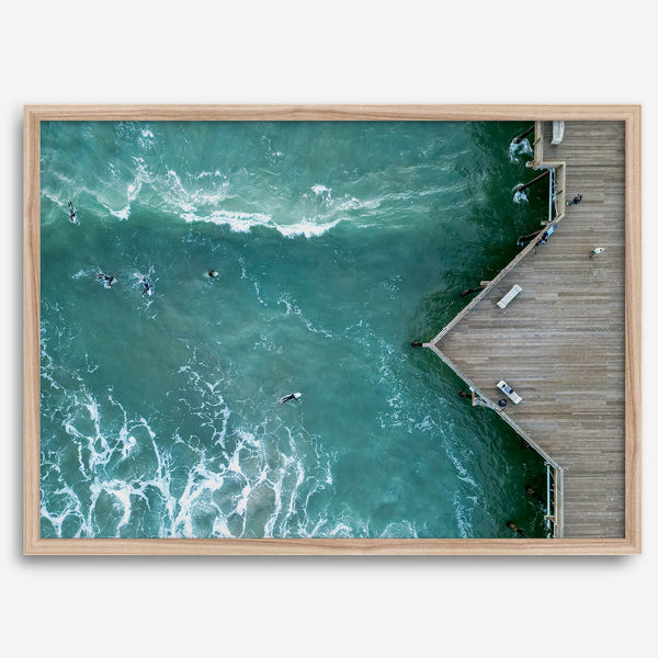 Aerial photo of Pismo Pier with surfers and turquoise ocean waves, ideal for coastal wall decor.