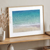 This fine art aerial beach print showcases the mesmerizing colors of the ocean in vivid detail. From the deep blue depths to the vibrant greenish turquoise blue, transitioning to the golden sandy beach and the crashing white surf.