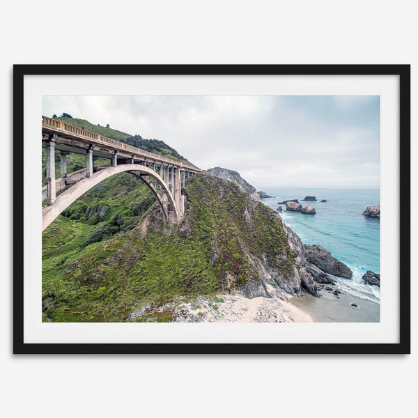 A fine art ocean print of one of the most iconic spots in the famous Route 1 in California - Bixby Bridge near Big Sur. Shot in a unique wide angle that captures the bridge, cliffs, the ocean, and the stunning beach below.