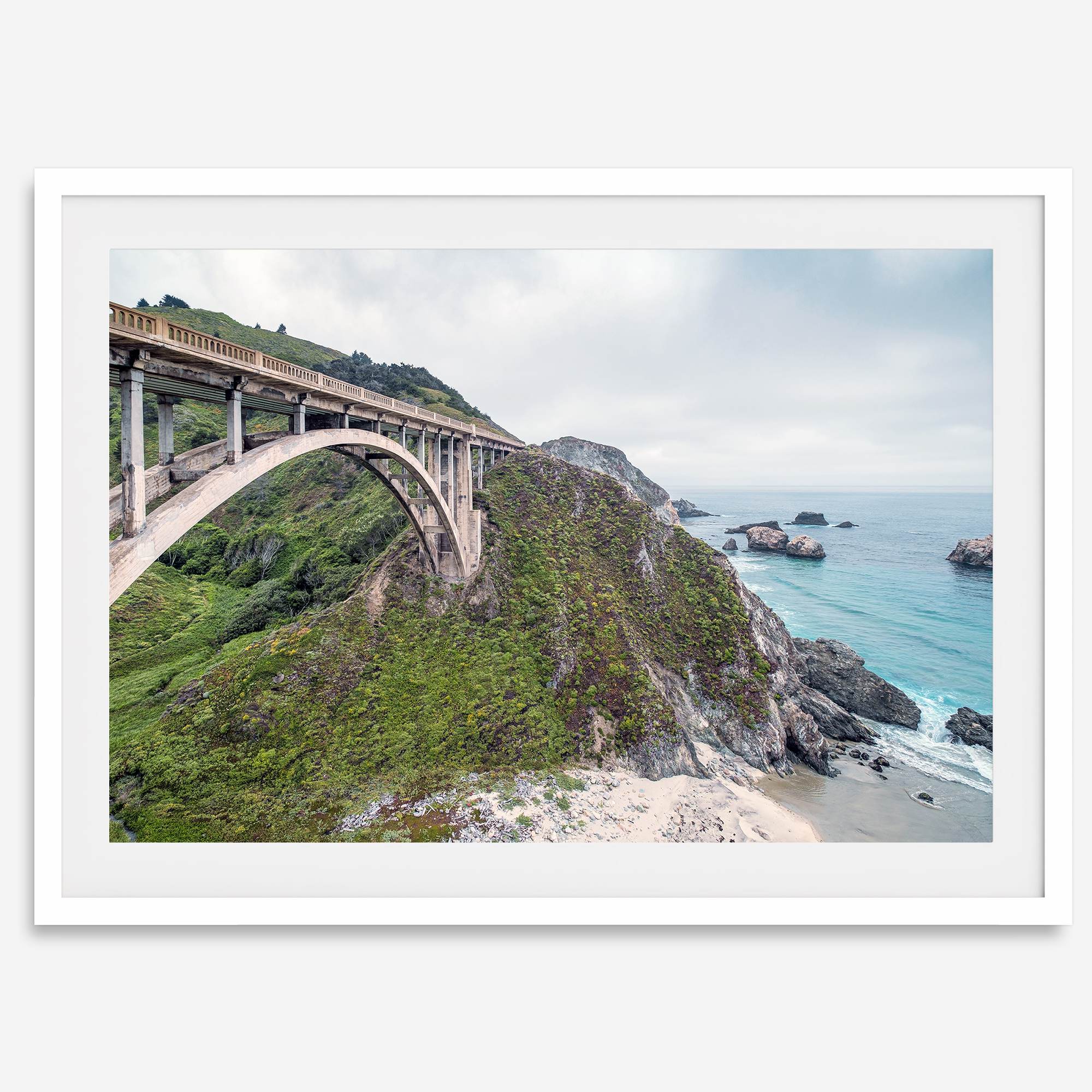 A fine art ocean print of one of the most iconic spots in the famous Route 1 in California - Bixby Bridge near Big Sur. Shot in a unique wide angle that captures the bridge, cliffs, the ocean, and the stunning beach below.