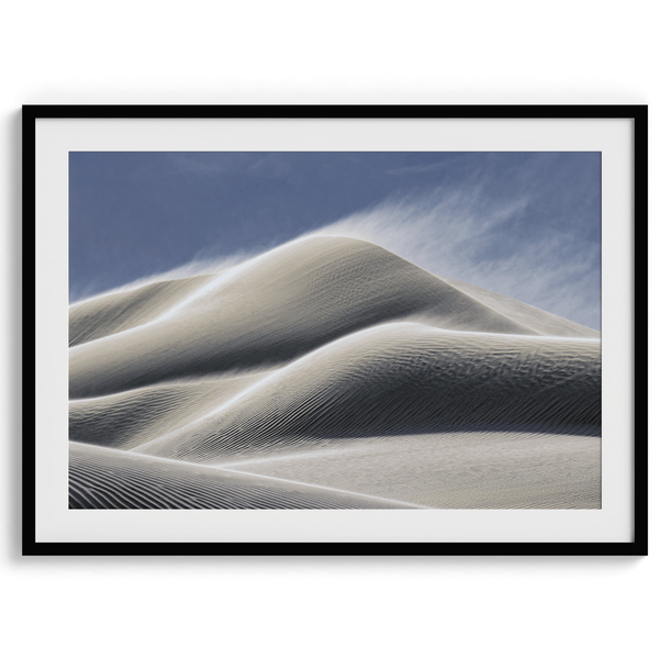 Fine art photo of Mesquite Flat Sand Dunes in Death Valley at golden hour. Windblown sand creates textured patterns across the immense dunes, bathed in warm light.