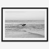 A fine art photography print capturing a female surfer walking back from the ocean at sunset with waves breaking in the foreground, capturing the end of a surf session.