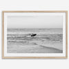 A fine art photography print capturing a female surfer walking back from the ocean at sunset with waves breaking in the foreground, capturing the end of a surf session.