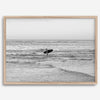 A fine art photography print capturing a female surfer walking back from the ocean at sunset with waves breaking in the foreground, capturing the end of a surf session.