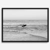 A fine art photography print capturing a female surfer walking back from the ocean at sunset with waves breaking in the foreground, capturing the end of a surf session.