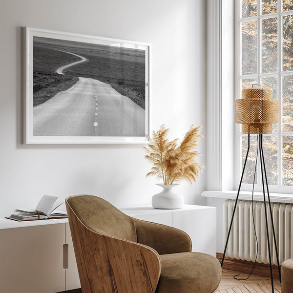 Black and white fine art photo of a winding desert road stretching through a vast minimalist landscape.