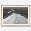 Black and white fine art photo of a winding desert road stretching through a vast minimalist landscape.
