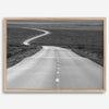 Black and white fine art photo of a winding desert road stretching through a vast minimalist landscape.
