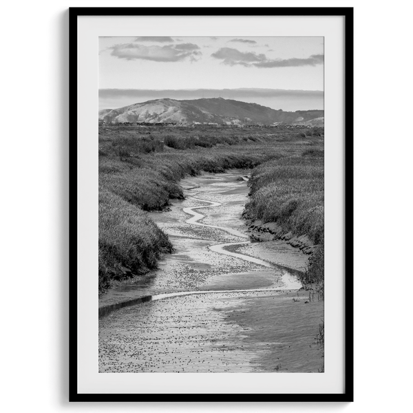 A captivating fine art black and white nature portrait print that transports viewers to the enchanting marshlands of California, where a winding little river weaves its way through a picturesque landscape.