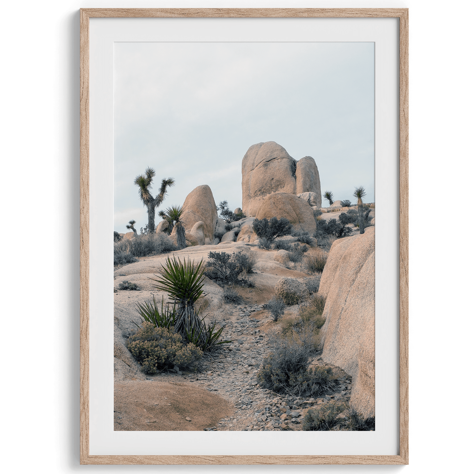 A fine art framed desert print featuring unique rock formations, desert plants, and Joshua Trees.